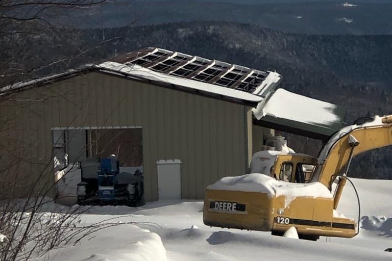 Steel building with rooftop solar panels after a heavy mountain snowfall